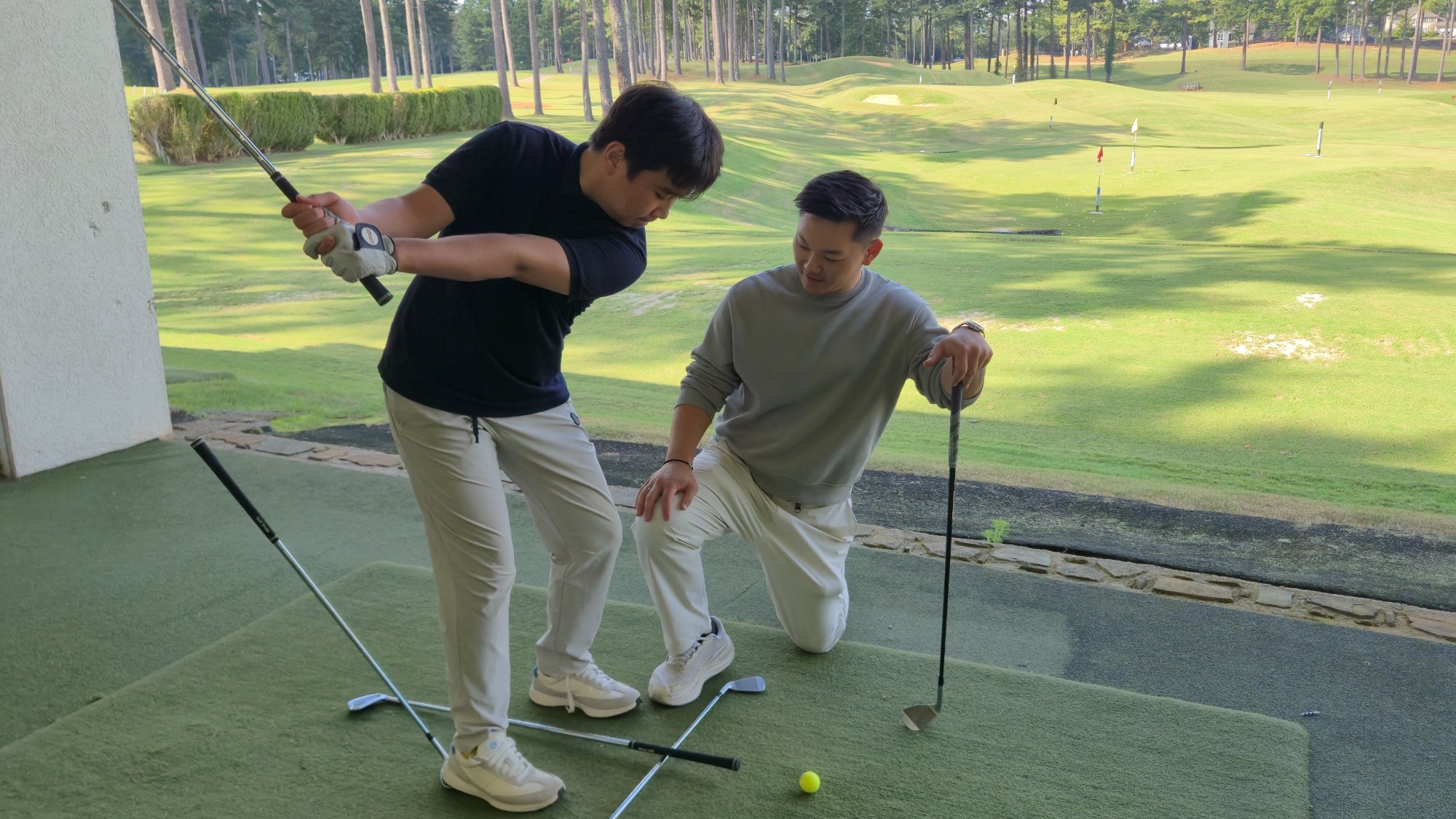 감독이 무릎을 꿇고 학생의 스윙을 지켜보는 장면